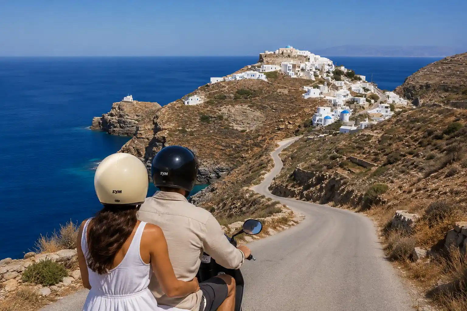 Couple riding a scooter on a coastal road in Sifnos